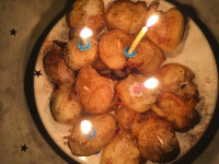 birthday candles on sweet fritters with cinammon on a plate