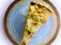 a peace of cake with meringue on a red and gold rim plate