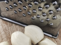 cloves of garlic are rubbed by the right grater for a tzatziki