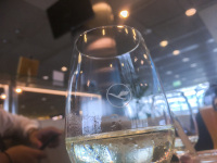 white wine in a glass with the emblem of lufhansa in the lufthansa lounge
