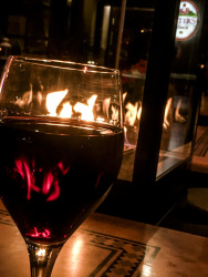a fire lantern is reflecting in a glass of red wine