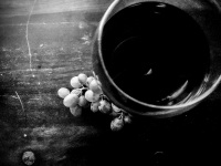 a glass of red wine and grapes on a dark wooden table