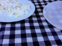 three white plates with potatoes and tzatziki on a blue white checkered tablecloth