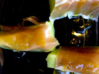some in serrano ham wrapped peaces of honeydew melon on a black plate