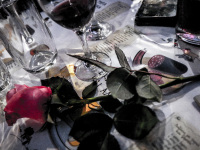 a pink rose and glasses of red wine are on a tablecloth wichh is painted with sausages