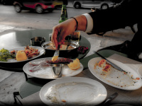 at a tasting greek food on half full and half empty plates someone takes some mustard