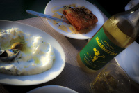malamatina retsina in a glass and in a bottle to that a plate of tzatziki and a plate of feta with honey