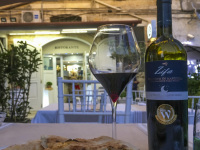 some peaces of pizza bread and a primitivo di manduria in front of an illuminated trattoria
