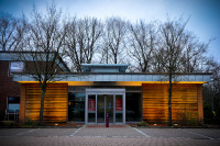 in front of bare oaks stands the nice illuminated wooden building of the sparkasse in unterlüß in lower saxony