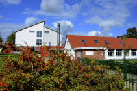 behind an autmnal bush with red berries you see the anne frank school in bergen in lower saxony