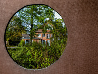through a hole of a wooden goal wall you see the red building of the evangelical education center in hermannsburg in lower saxony