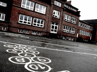 there are painted many white numbers on a schoolyard, in the background you see the red building of the hinrich-wolff-school in bergen in lower saxony