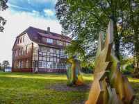 abstract artworks in front of a half-timbered house and some trees
