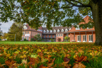 behind a lawn with autumn leaves you see the red building of the evangelical education center in hermannsburg in lower saxony