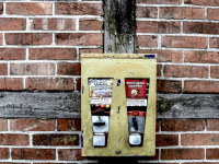 an old yellow gumball machine hangs on a facade of a half-timbered house with red bricks