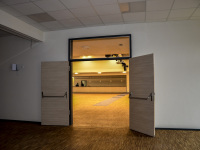 an open wooden door is leading to an illuminated event hall