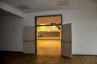 an open wooden door is leading to an illuminated event hall
