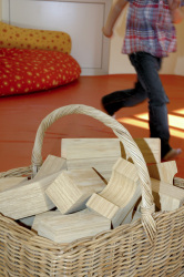 big wooden building blocks are laying in a basket in a kindergarden