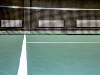 a tennis court with three white heater in the background