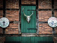 a half-timbered house with red bricks, green wooden doors and a deer antler near bergen in lower saxony