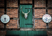 a half-timbered house with red bricks, green wooden doors and a deer antler near bergen in lower saxony