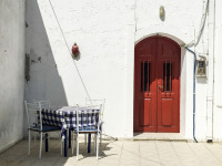 a red wooden door and a table with a blue-white checkered tablecloth in an inner courtyard in lardos on rhodes