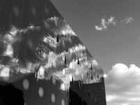 the sky with some clowds is reflected in the front of a high-rise building in hamburg, black-and-white
