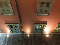 an illuminated pink facade with wooden light green shutters by night in nafplion