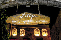 a wooden sign in the old town of rhodes points out of letty\'s luxury apartment