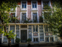the beautiful facade of a house with big windows and trees in front of it in makriyanni in athens