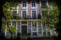 the beautiful facade of a house with big windows and trees in front of it in makriyanni in athens