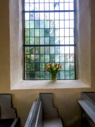 a bouquet of tulips in front a glass mosaic window in the church St. petri in großburgwedel in lower saxony