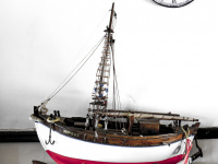 an old clock and a model boat in front of a white wall in the elafos hotel on rhodes