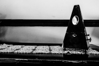 an old metronome and a lace blanket on a piano in the lounge of the elafos hotel on rhodes, black-and-white