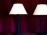 two table lamps on an old wooden table in front of a wine red curtain in the elafos hotel on rhodes