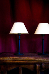 two table lamps on an old wooden table in front of a wine red curtain in the elafos hotel on rhodes