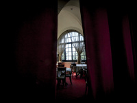 through wine red curtains you see tables and chairs of the restaurant of the elafos hotel on rhodes
