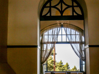 through a round arch you see the old wooden furniture of the restaurant of the elafos hotel on rhodes
