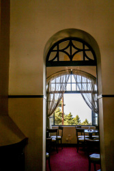 through a round arch you see the old wooden furniture of the restaurant of the elafos hotel on rhodes