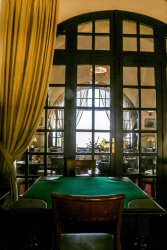a green poker table in front of a dark wooden lattice door in the hotel elafos on Rhodes
