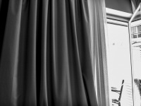 a curtain and a balkony door in john\'s hotel in chalkida, black-and-white
