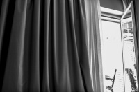 a curtain and a balkony door in john\'s hotel in chalkida, black-and-white