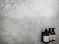 three brown bottles of shampoo, conditioner and showergel in front of grey tiles in a room of the hotel nh collection köln mediapark in cologne