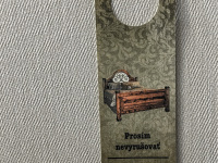 a a grey wall hangs a olive green sign with lettering please do not disturb in english and in slovak in the esprit hotel in bratislava