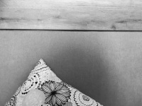 a peace of a floral designe pillow in front of an end of a bed in a room of the hotel acropolis vision in athens, black-and-white