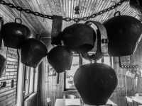 big cowbells in the rustic wooden hut of a restaurant near kalavrita in greece, black-and-white