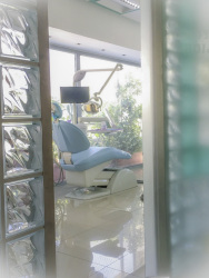 through a door next to big glass blocks you look on a light blue dentist chair in a dental practice in rhodes city