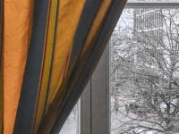 in the hotel XII apostel in colgogne you see behind a blue and yellow curtain through the window the winterly heumarkt in cologne