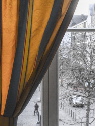 in the hotel XII apostel in colgogne you see behind a blue and yellow curtain through the window the winterly heumarkt in cologne