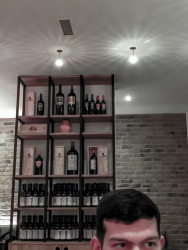 someone is sittingin front of a shelf with bottles of redwine in the saro tapas bar & lounge in osnabrück